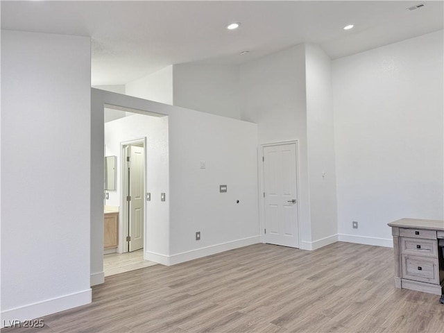 spare room featuring high vaulted ceiling and light hardwood / wood-style floors