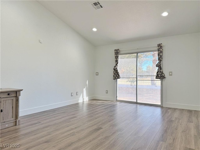 spare room featuring lofted ceiling and light hardwood / wood-style floors