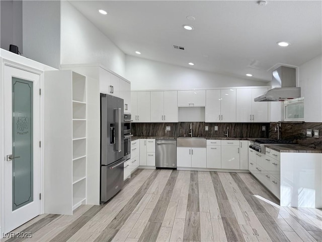 kitchen featuring extractor fan, high vaulted ceiling, white cabinetry, sink, and stainless steel appliances