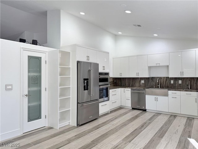 kitchen with sink, white cabinetry, high vaulted ceiling, stainless steel appliances, and decorative backsplash