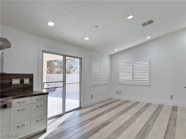 unfurnished dining area featuring light hardwood / wood-style flooring and vaulted ceiling