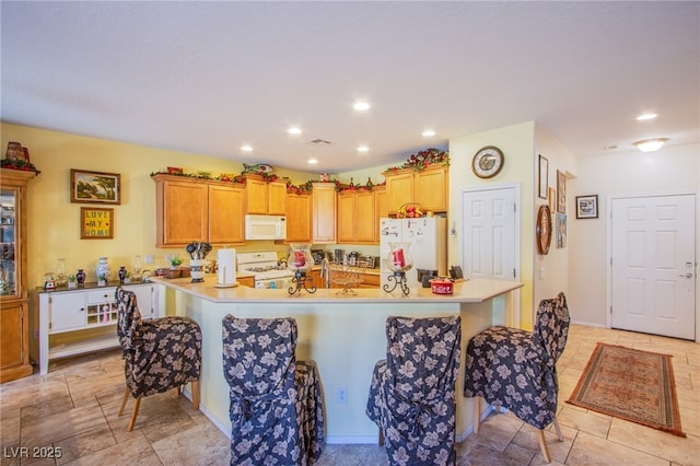 kitchen featuring white appliances, a center island, and a breakfast bar area