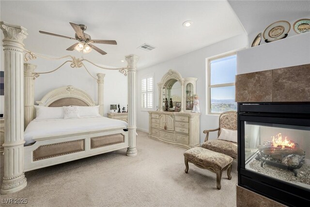 carpeted bedroom featuring a tile fireplace and ceiling fan