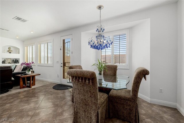 dining area featuring dark tile patterned flooring, a notable chandelier, a wealth of natural light, and built in shelves