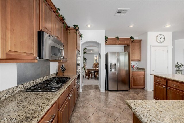 kitchen featuring appliances with stainless steel finishes, light tile patterned floors, and light stone counters