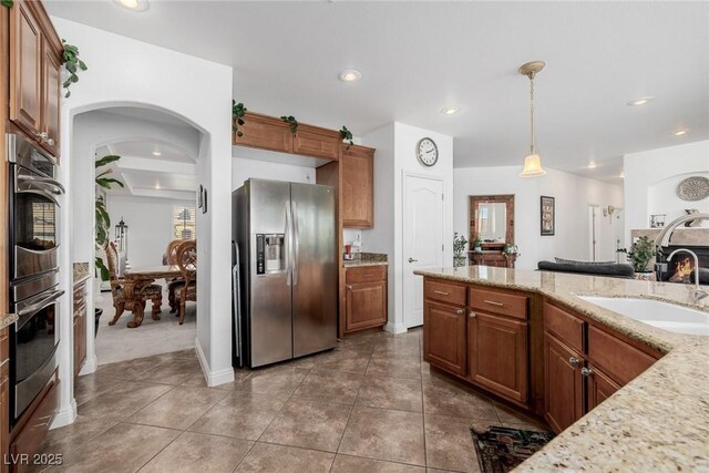 kitchen featuring light stone countertops, appliances with stainless steel finishes, dark tile patterned floors, sink, and decorative light fixtures