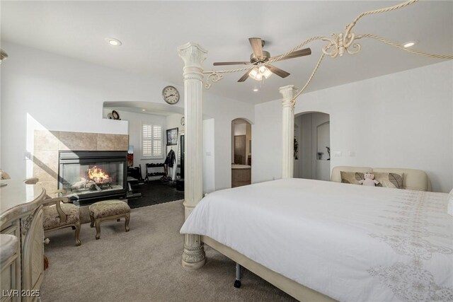 carpeted bedroom with a tiled fireplace and ceiling fan