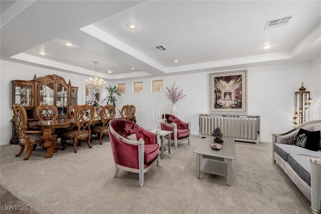 carpeted living room featuring a tray ceiling and a notable chandelier