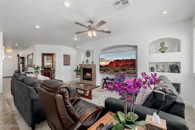 tiled living room with ceiling fan and a tiled fireplace