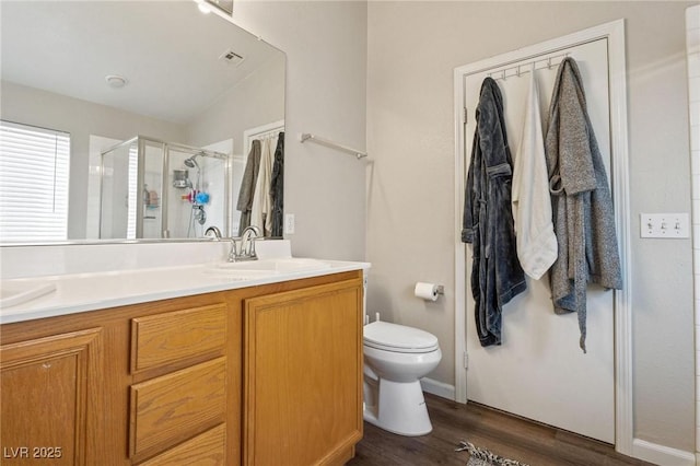 bathroom with toilet, vanity, a shower with shower door, and wood-type flooring