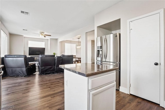 kitchen with stainless steel fridge, dark hardwood / wood-style flooring, dark stone counters, ceiling fan, and white cabinetry