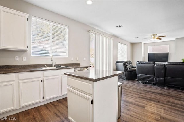 kitchen featuring white cabinets, a kitchen island, sink, and dark wood-type flooring