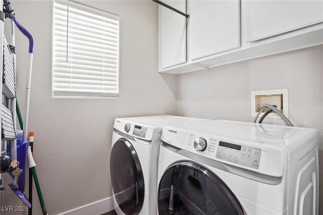 clothes washing area with separate washer and dryer and cabinets