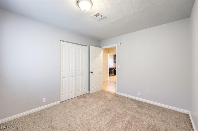 unfurnished bedroom with light carpet and a closet