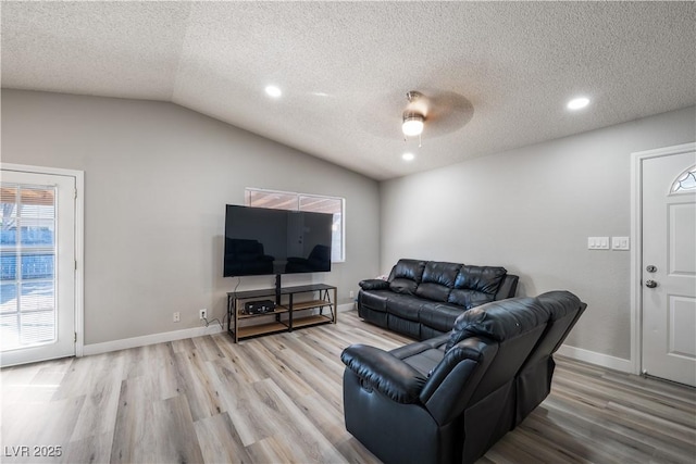 living room featuring ceiling fan, light hardwood / wood-style flooring, a textured ceiling, and vaulted ceiling