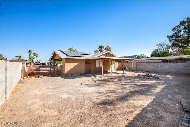 rear view of property featuring solar panels, a patio, and a fire pit