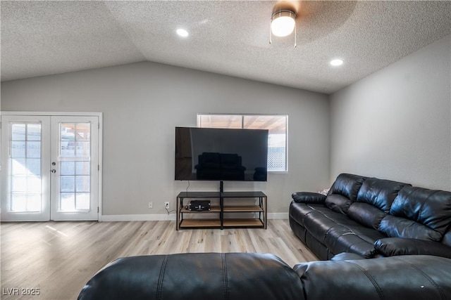 living room with french doors, a textured ceiling, lofted ceiling, and hardwood / wood-style floors