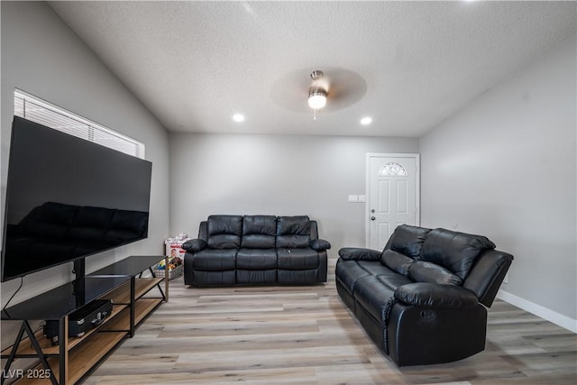 living room featuring ceiling fan, a textured ceiling, and light hardwood / wood-style flooring