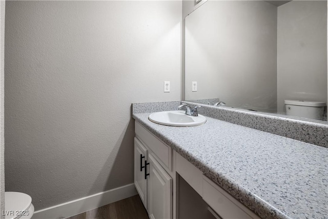 bathroom featuring vanity, hardwood / wood-style flooring, and toilet