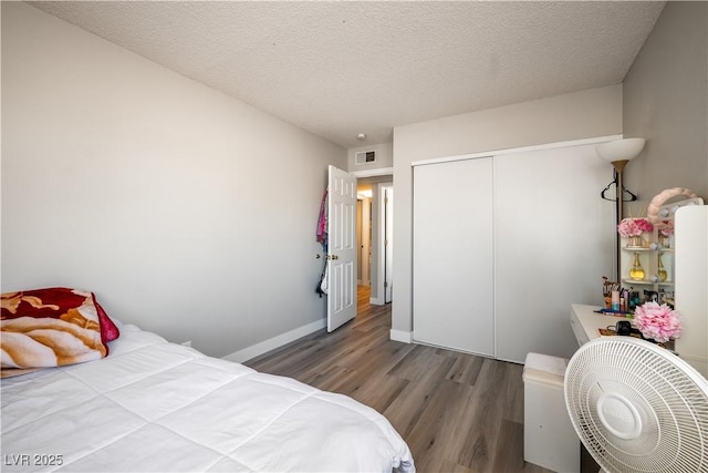 bedroom featuring a closet, a textured ceiling, and dark wood-type flooring