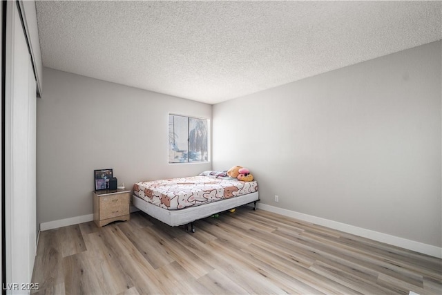 bedroom with a textured ceiling and light wood-type flooring