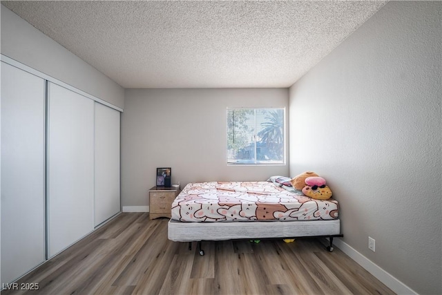 bedroom with a closet, a textured ceiling, and hardwood / wood-style flooring