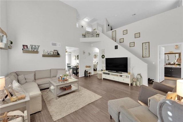 living room featuring ceiling fan, wood-type flooring, and a high ceiling