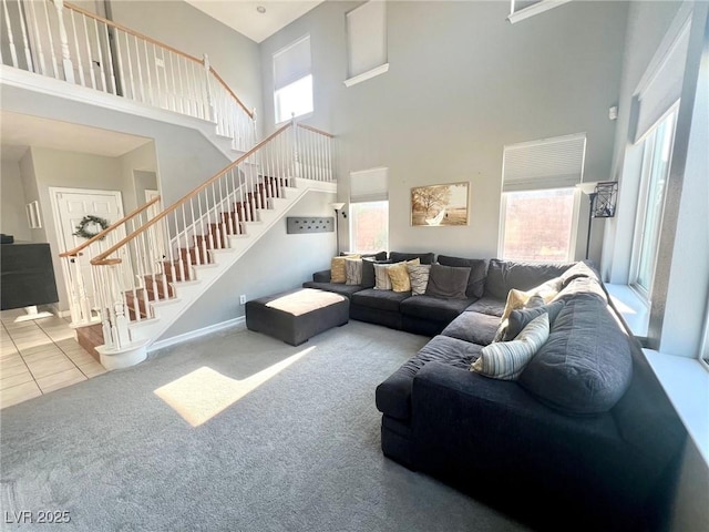 living room with a healthy amount of sunlight, carpet, and a towering ceiling