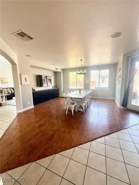 unfurnished dining area featuring a chandelier, a textured ceiling, and light wood-type flooring