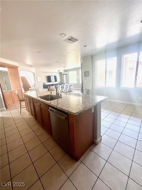 kitchen featuring light tile patterned flooring, an island with sink, dishwasher, and sink