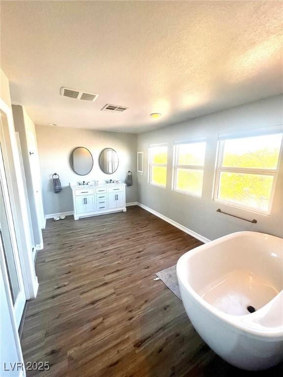 bathroom with a tub, sink, hardwood / wood-style floors, and a textured ceiling