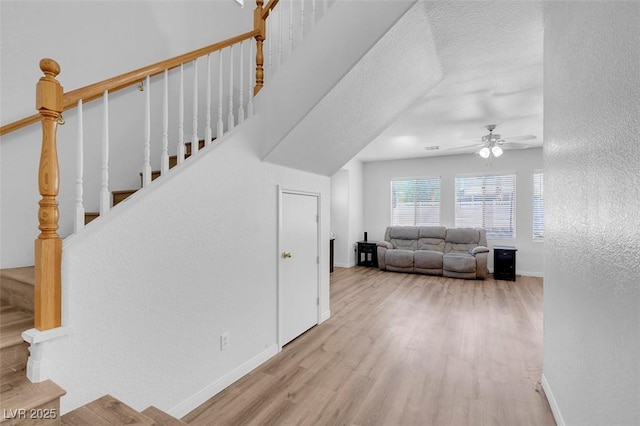 stairway with ceiling fan, hardwood / wood-style floors, and a textured ceiling