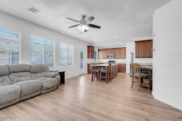 living room with light hardwood / wood-style floors and ceiling fan