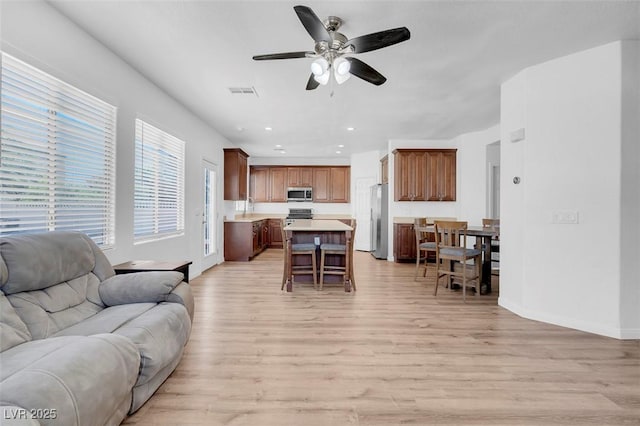 living room with ceiling fan, light wood-type flooring, and sink