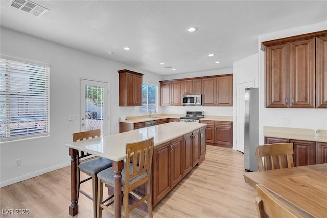 kitchen featuring a kitchen breakfast bar, a center island, stainless steel appliances, and light wood-type flooring