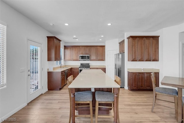 kitchen featuring a kitchen island, sink, stainless steel appliances, and light hardwood / wood-style flooring