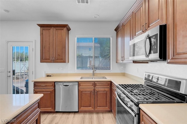 kitchen with appliances with stainless steel finishes, light wood-type flooring, and sink