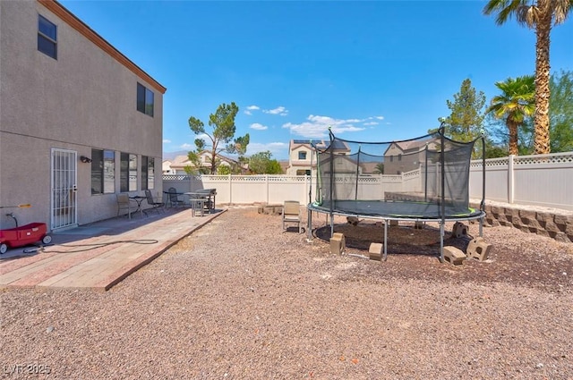 view of yard with a trampoline and a patio area