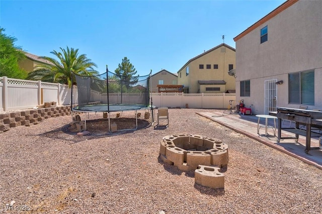 view of yard with a fire pit, a trampoline, and a patio