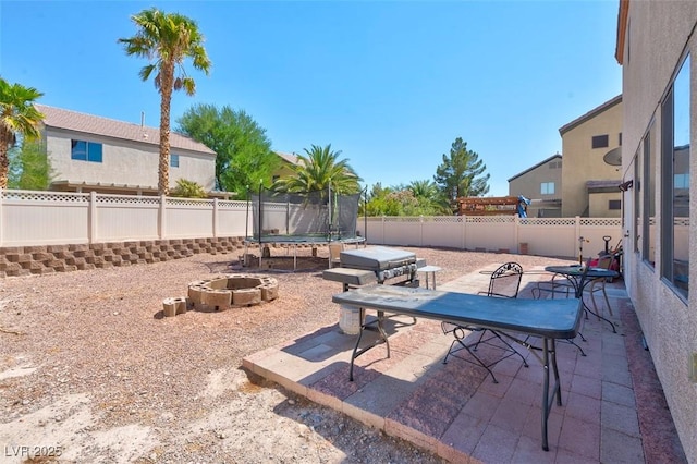 view of patio / terrace with a trampoline and an outdoor fire pit