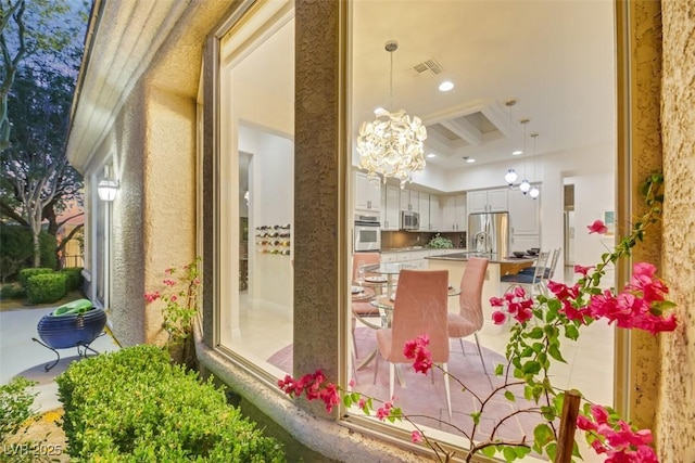 interior space featuring a breakfast bar, a raised ceiling, pendant lighting, stainless steel appliances, and white cabinets