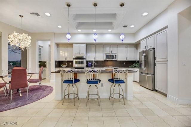 kitchen with stainless steel appliances, hanging light fixtures, backsplash, and a kitchen bar