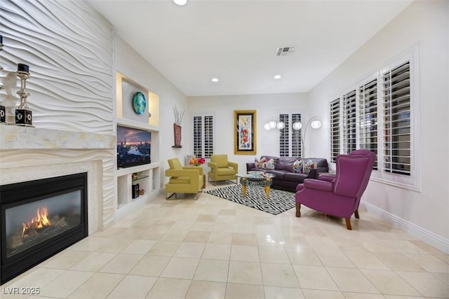 living room featuring a premium fireplace, light tile patterned floors, and built in shelves