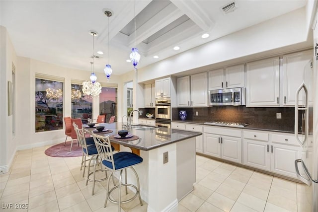 kitchen featuring stainless steel appliances, decorative light fixtures, sink, and white cabinets