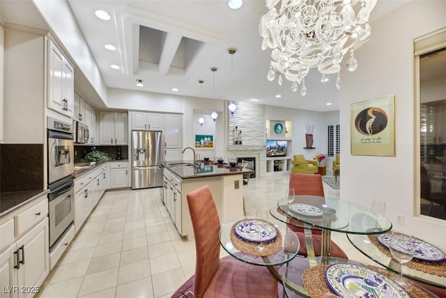 kitchen featuring tasteful backsplash, hanging light fixtures, light tile patterned floors, stainless steel appliances, and white cabinets