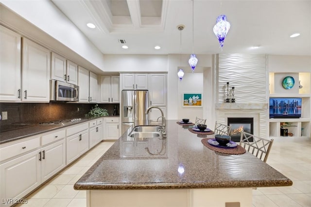 kitchen with a large island, sink, appliances with stainless steel finishes, white cabinets, and decorative light fixtures