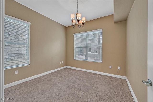 spare room featuring light carpet, an inviting chandelier, and baseboards