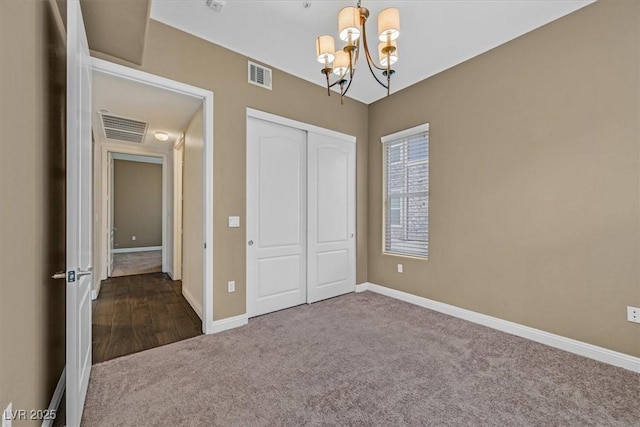 unfurnished bedroom with carpet floors, a closet, visible vents, and an inviting chandelier