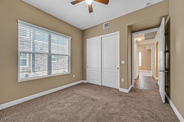 unfurnished bedroom with baseboards, visible vents, a closet, and light colored carpet