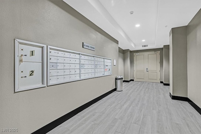 hallway with light wood-type flooring, mail area, baseboards, and recessed lighting